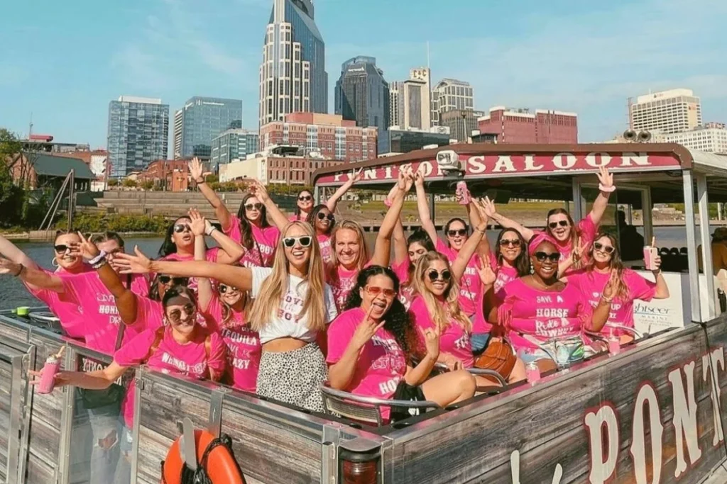 bachelorette party on a pontoon in nashville,bride wearing white and bachelorette group in matching pink shirts